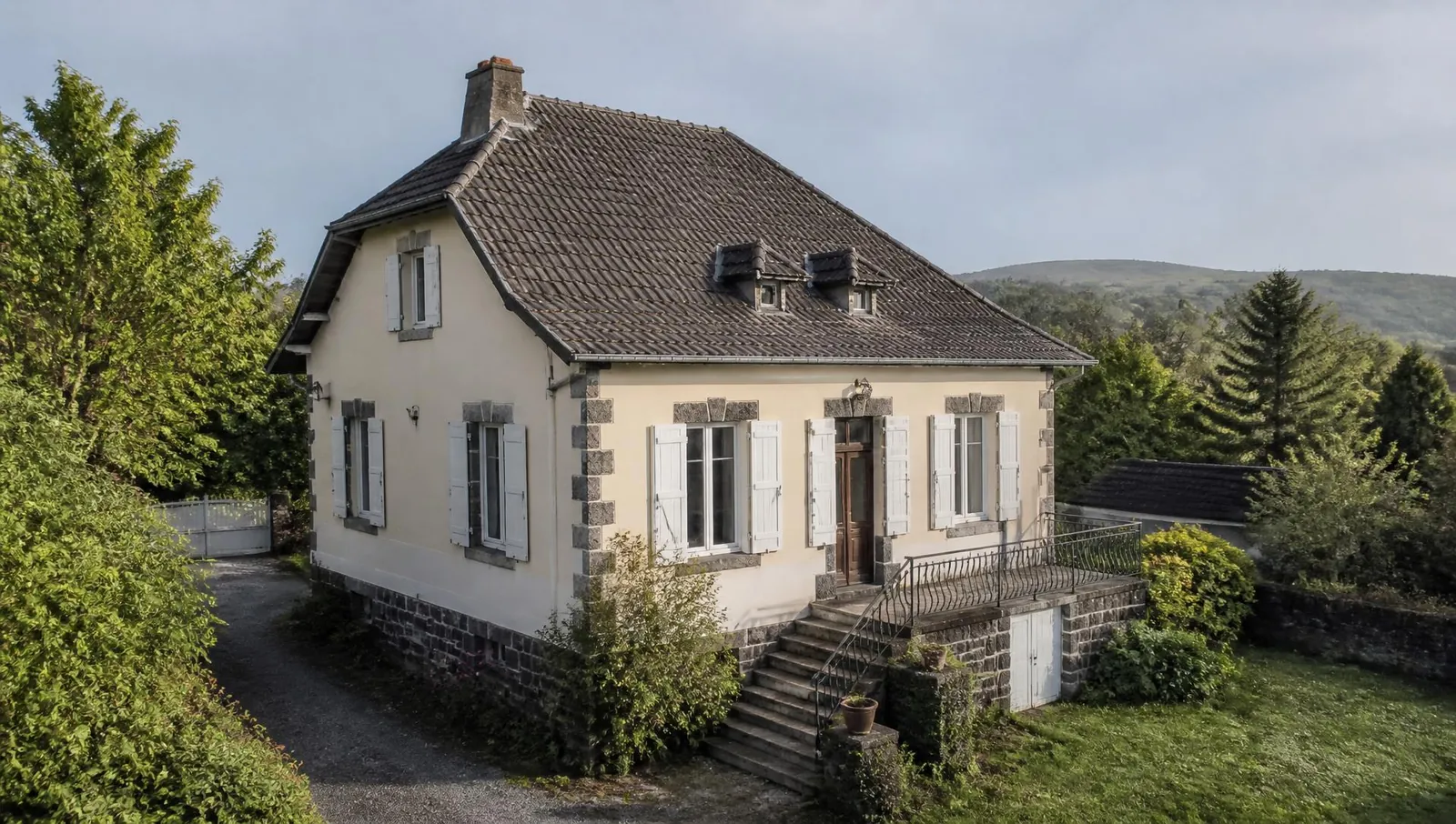 Maison auvergnate à toiture de tuiles et encadrements en pierre volcanique, vue en lumière naturelle